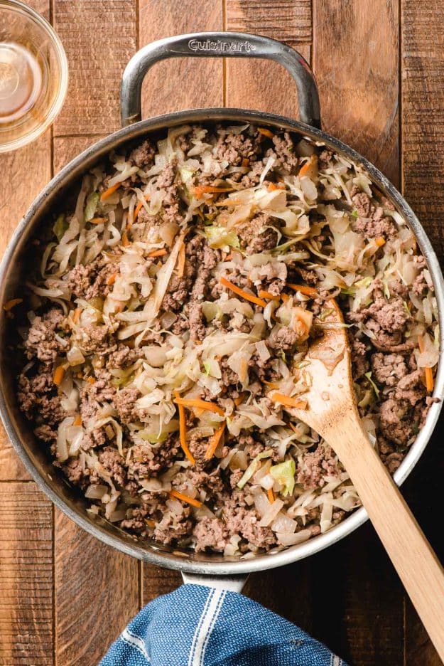 Ground beef, cabbage slaw, and onions sauteed in a large pan.