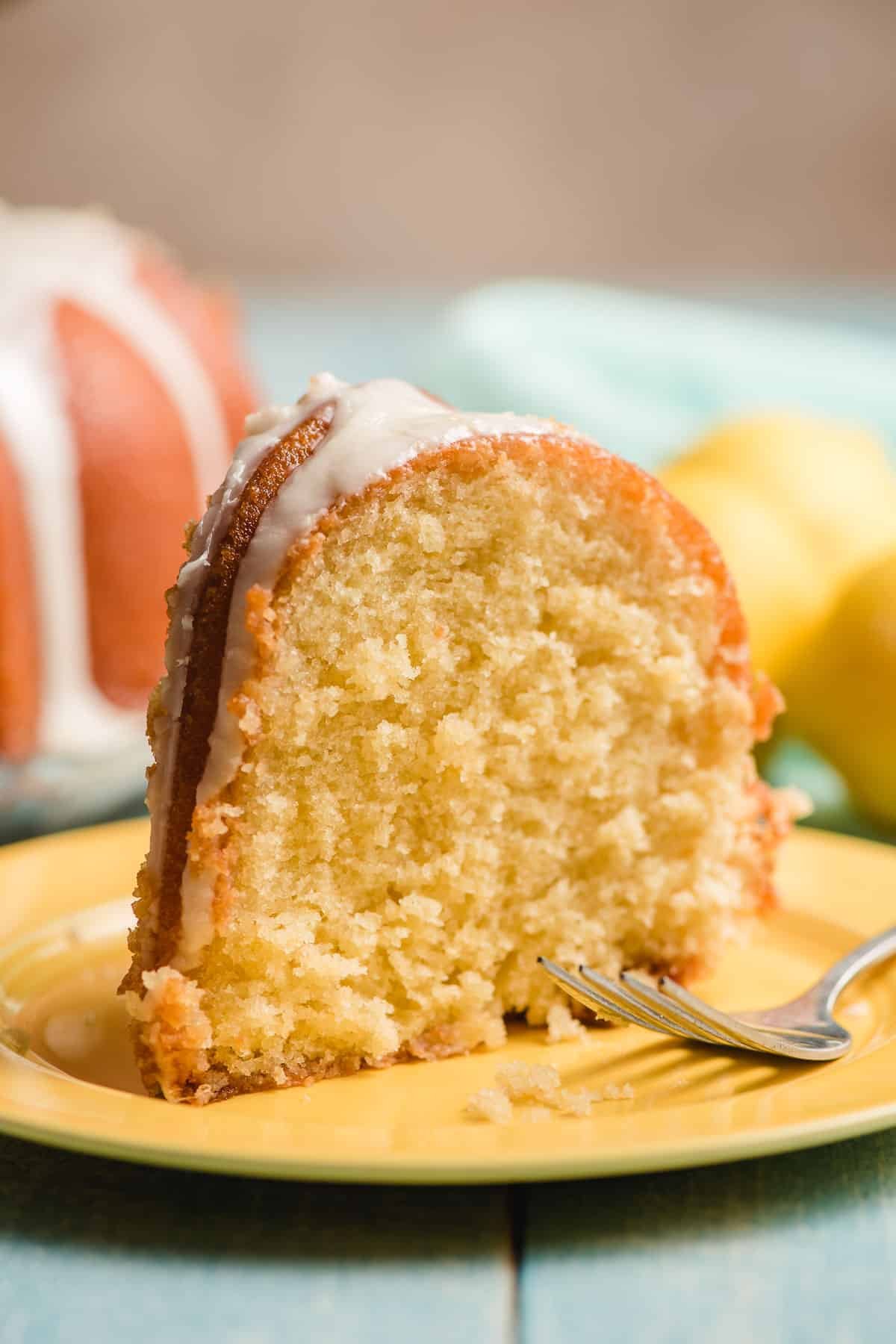Iced lemon bundt confection standing on a yellow plate.