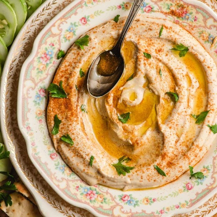 Creamy homemade hummus in a serving dish with spoon.