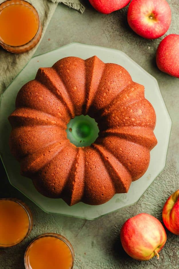 Freshly baked apple cider cake on a green cake stand.