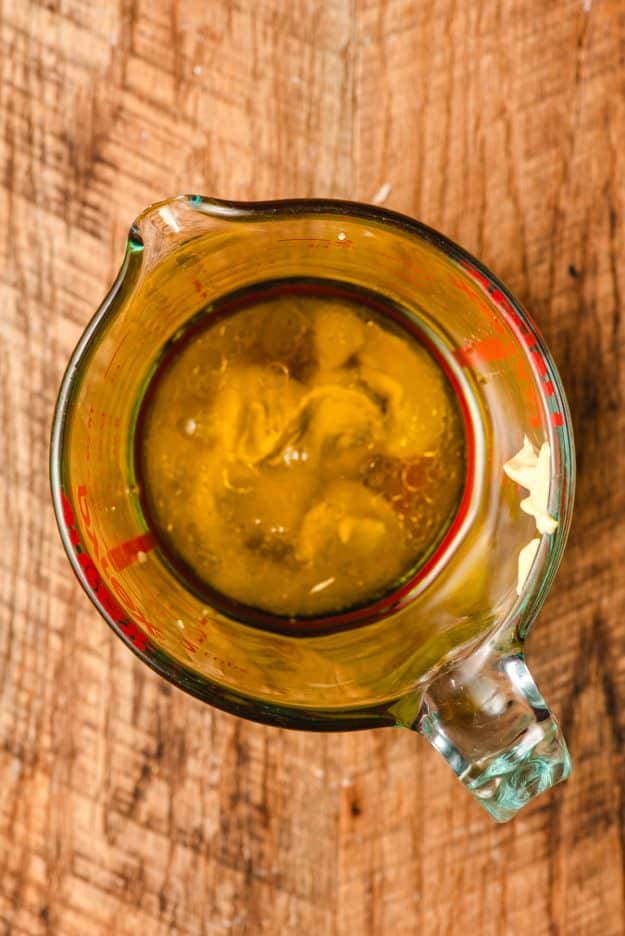 Dijon mustard, lemon juice, olive oil, vinegar, and maple syrup in a glass measuring cup.