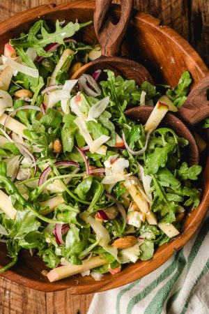 Arugula, apple, and fennel salad in a wooden bowl.