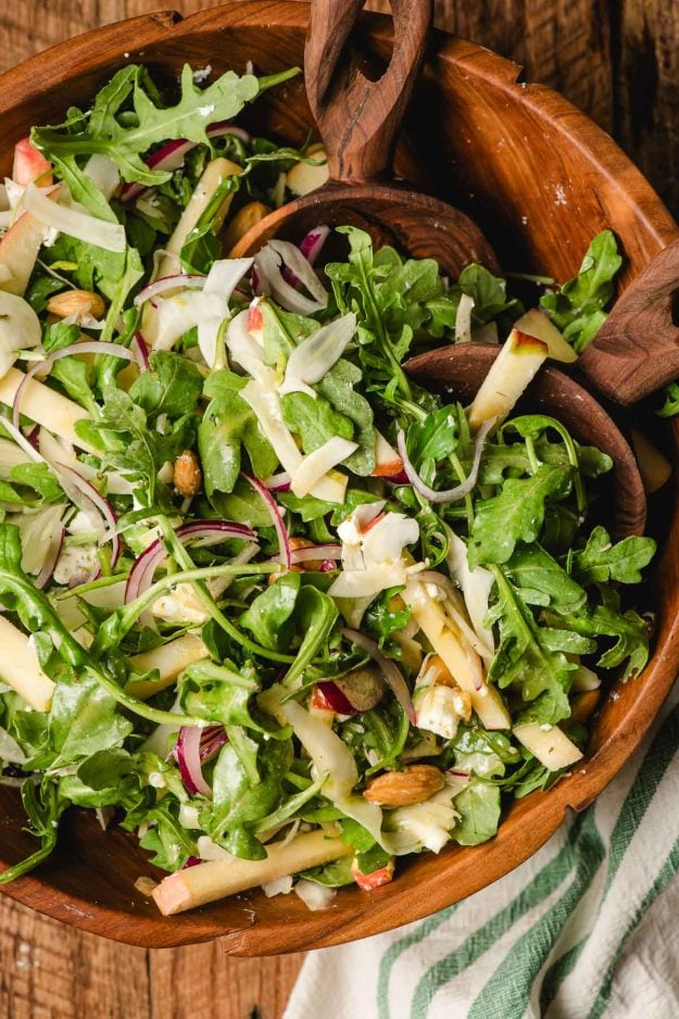 Arugula, apple, and fennel salad in a wooden bowl.