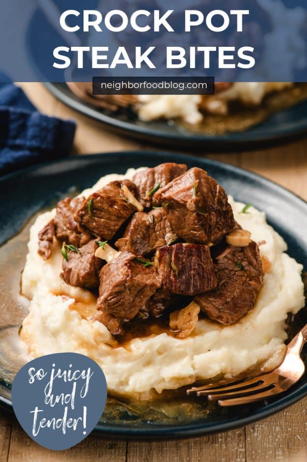 Slow cooker steak bites with garlic and thyme piled on a bed of mashed potatoes.