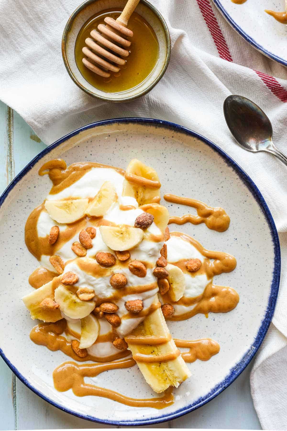 Sliced banana topped with yogurt, honey roasted peanuts, and honey peanut butter drizzle.