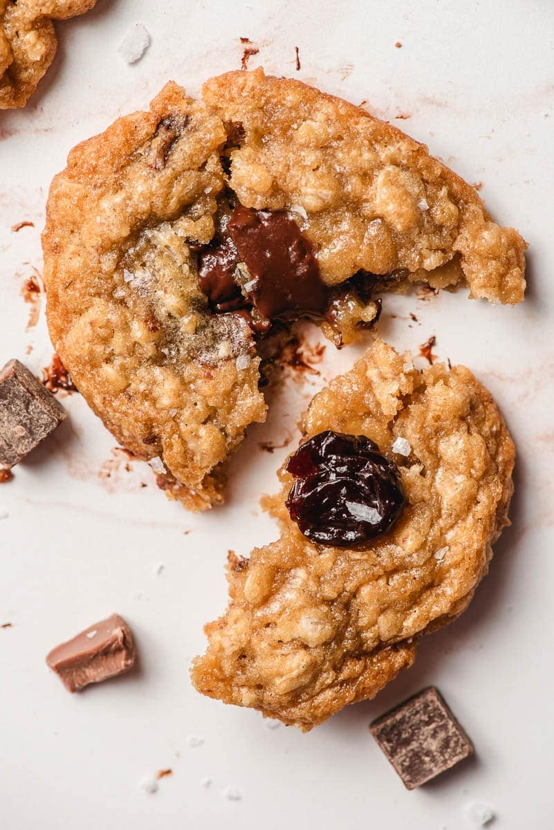 A cherry chocolate chip oatmeal cookie broken in half to show texture.