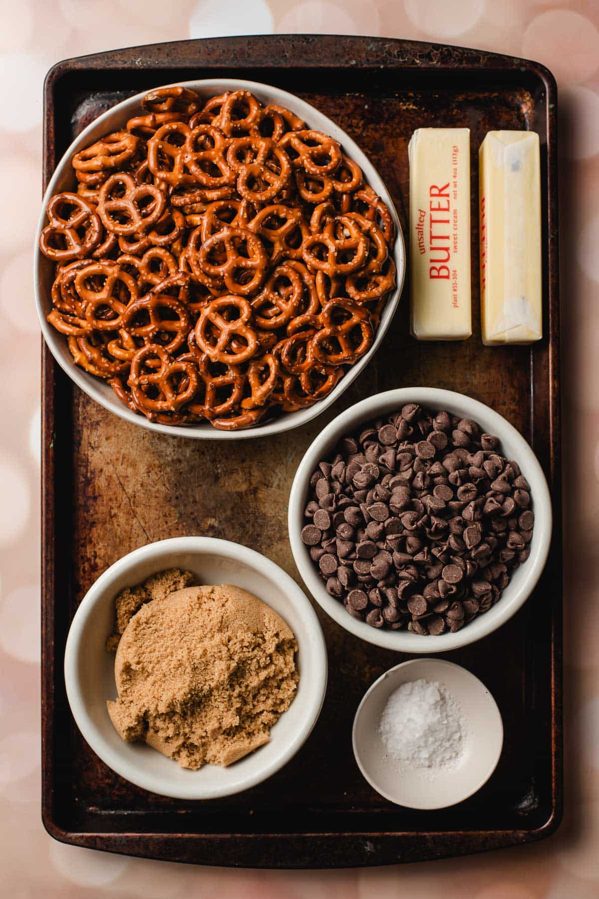 Baking sheet with chocolate chips, butter, pretzels, and brown sugar.