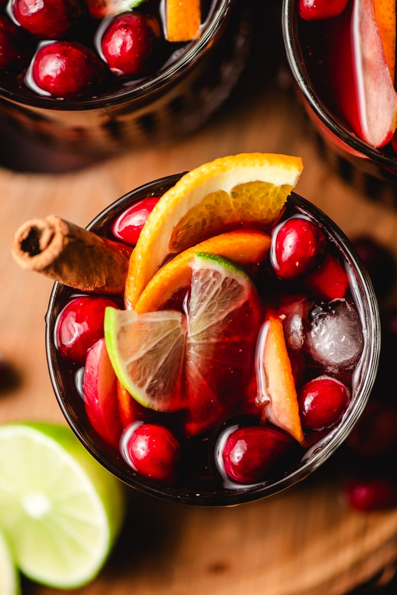 Pomegranate sangria in a glass with a cinnamon stick and fresh fruits.