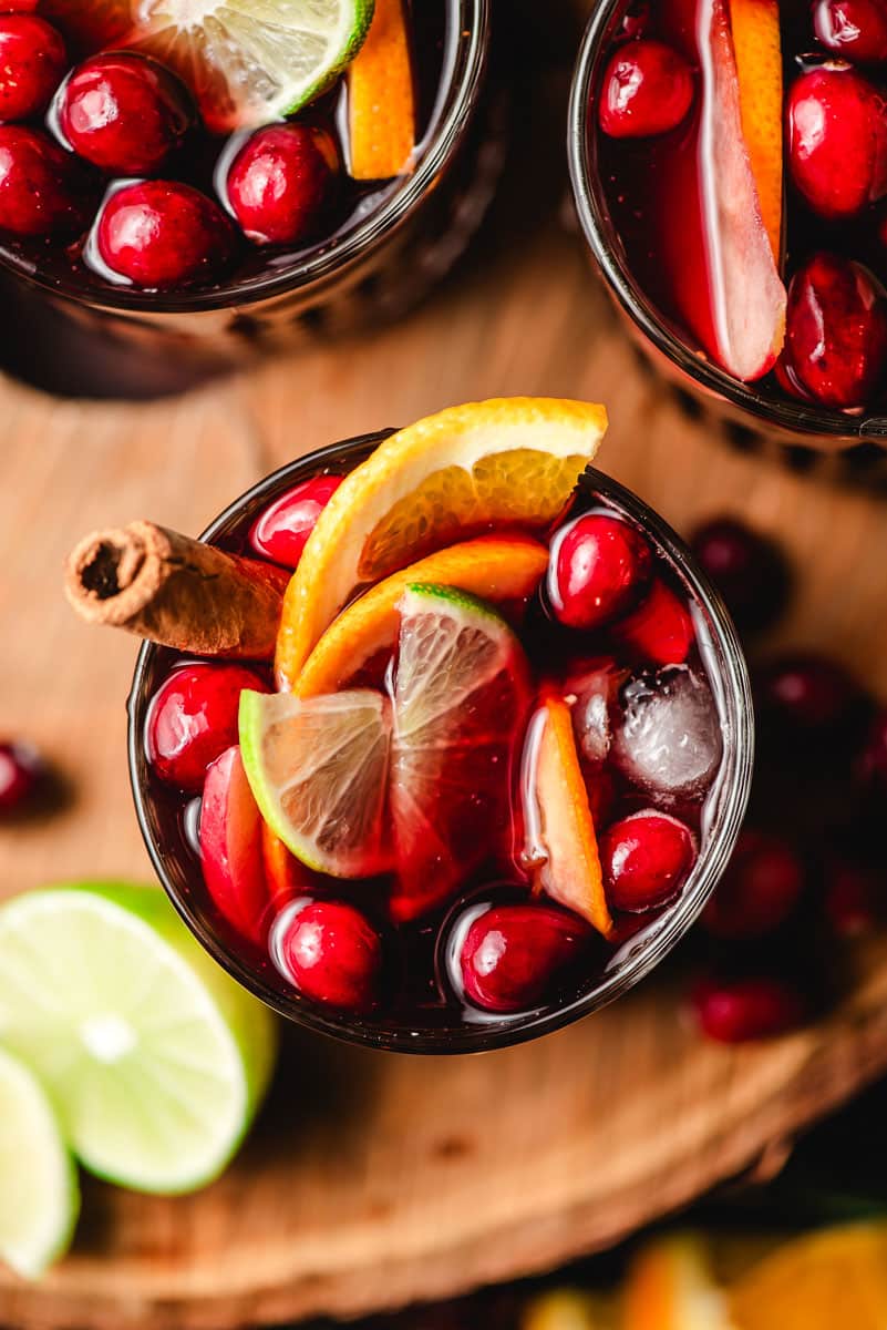 Holiday sangria with cranberries, lime, orange, and apples in a glass.
