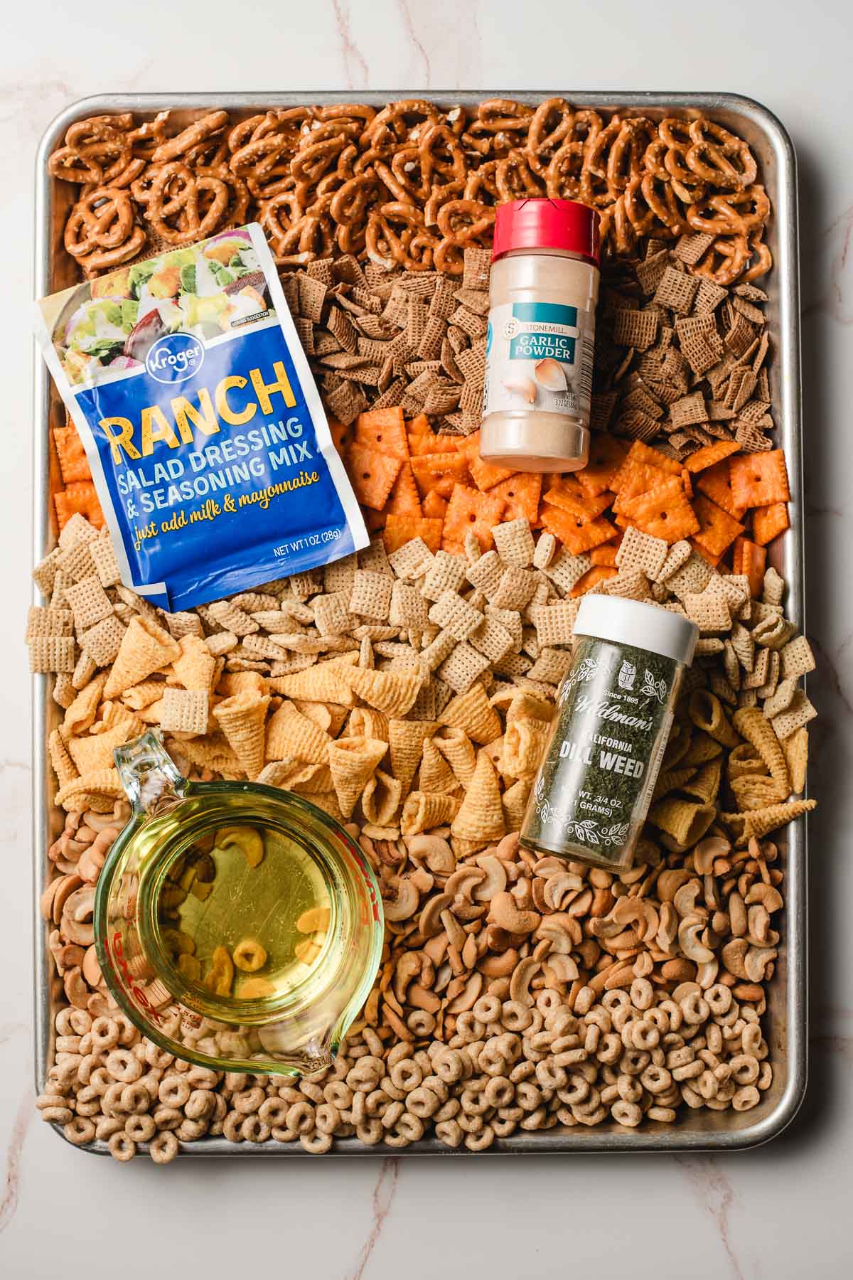 All of the ingredients for Ranch Chex Mix organized on a sultry sheet.