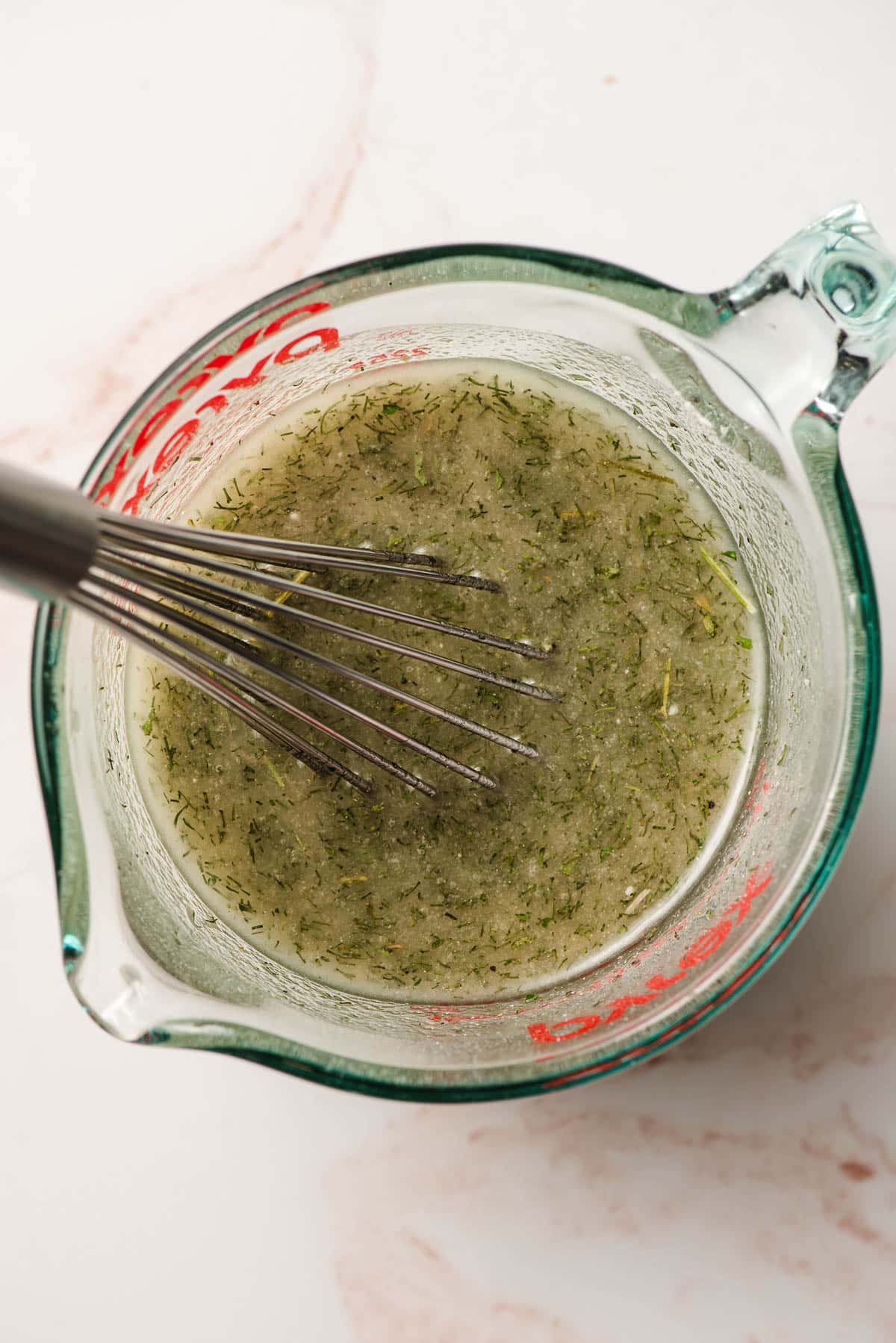 A ranch seasoning and oil mixture being whisked together in a glass measuring cup.