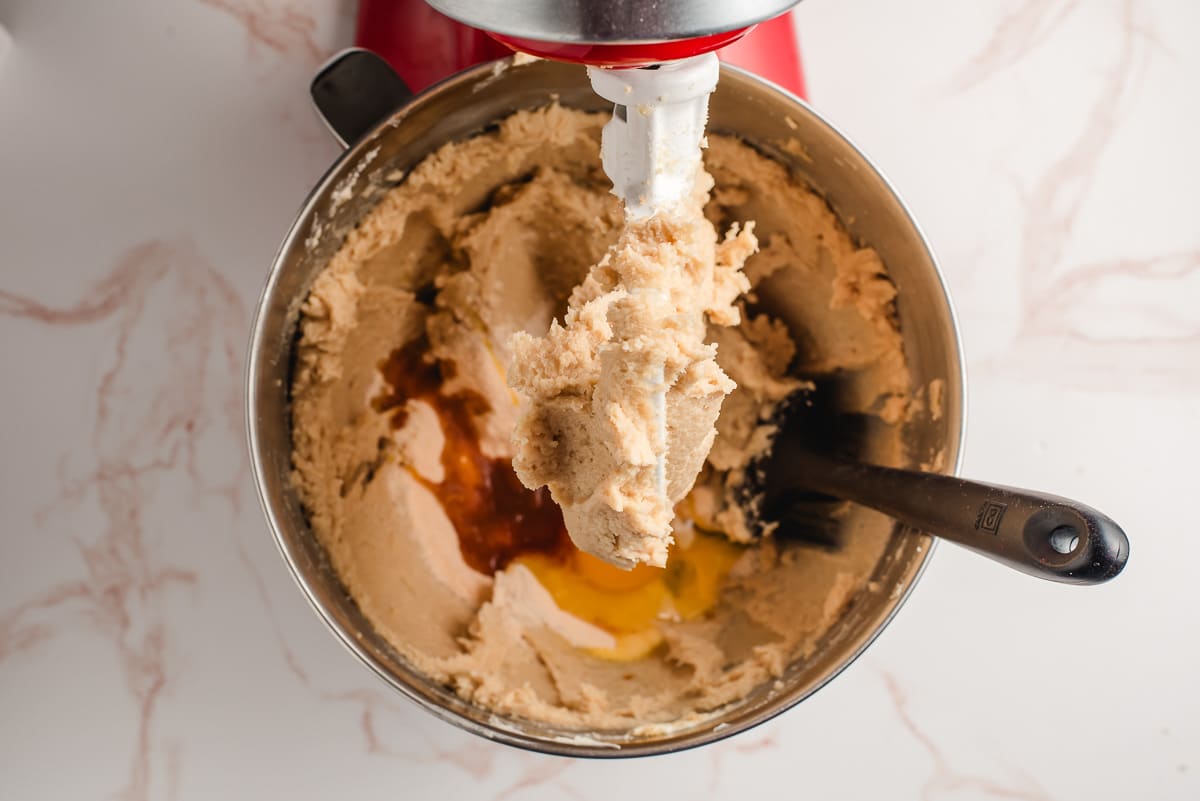 Eggs, vanilla, and pudding mix added to creamed butter and sugar in the bowl of an electric mixer.