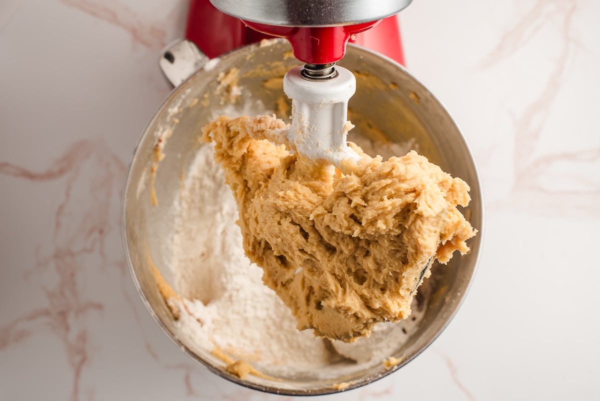 Flour, baking soda, and salt added to cookie dough in a mixer.