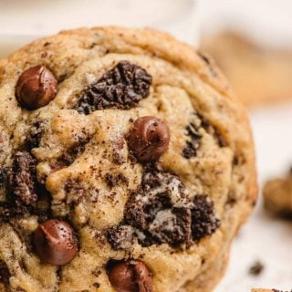 Oreo Chocolate Chip pudding cookie stood up on the side of a glass of milk.