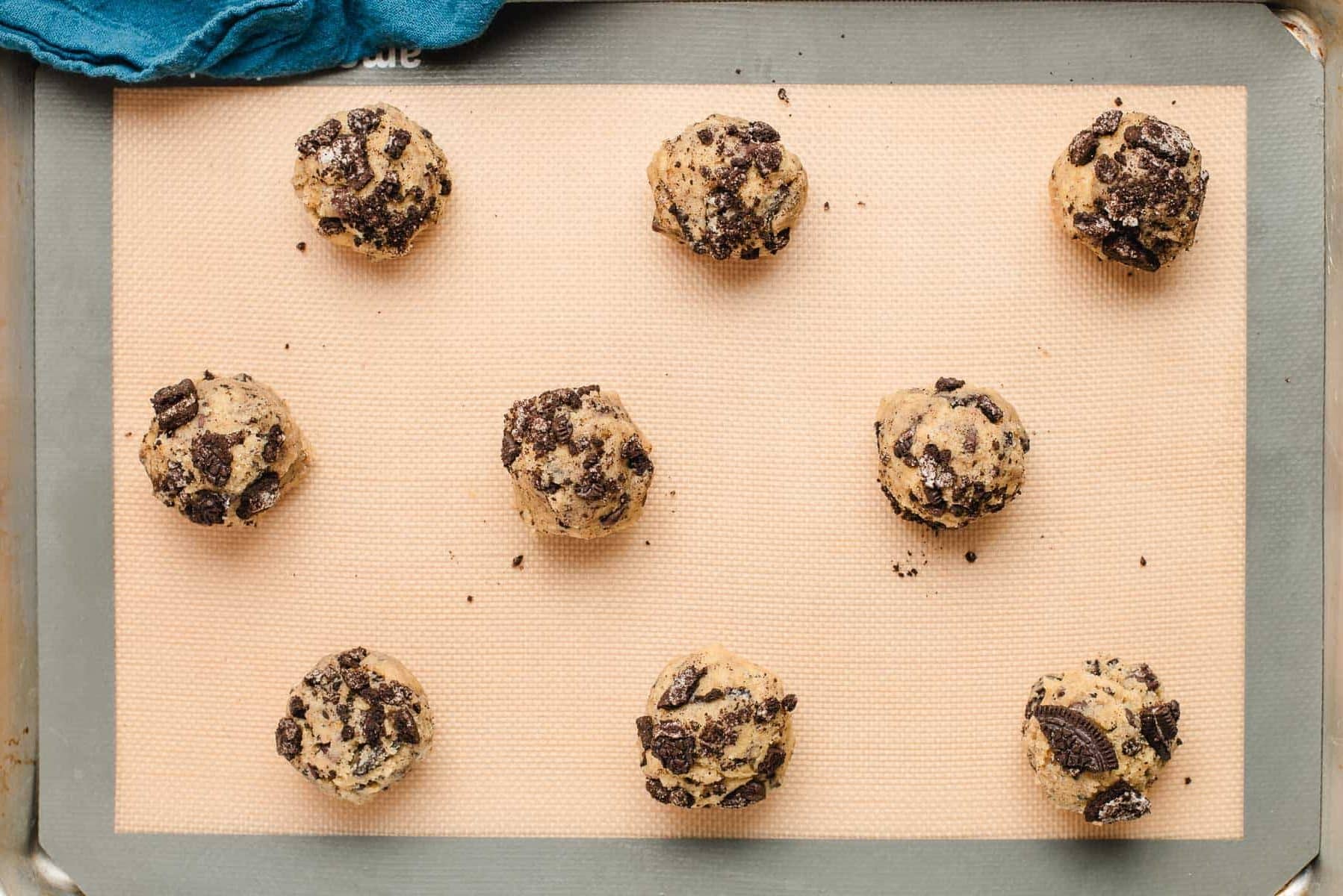 Balls of oreo cookie dough on a sheet pan.