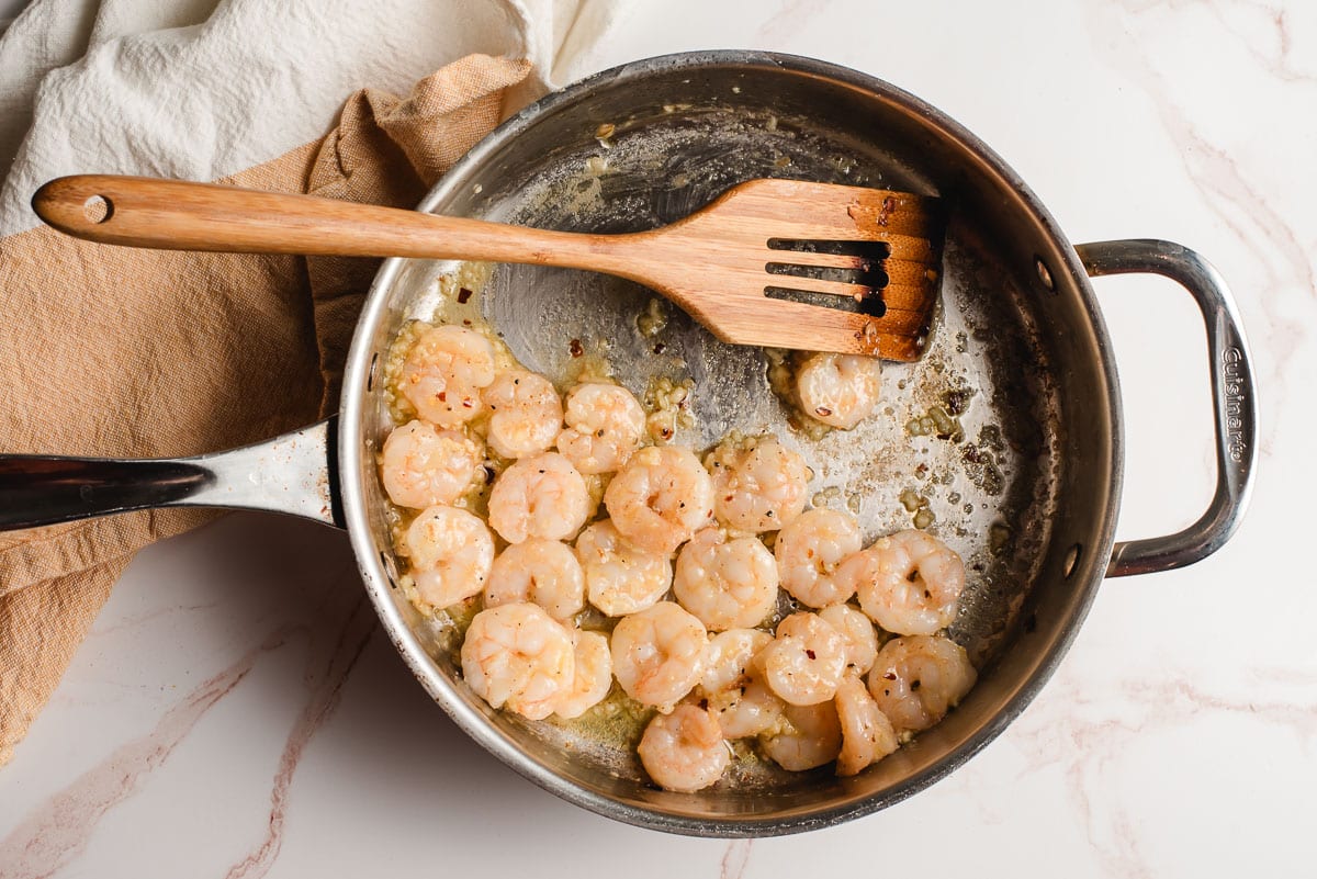 Sauteed shrimp with garlic, butter, and red pepper flakes in a stainless steel skillet.