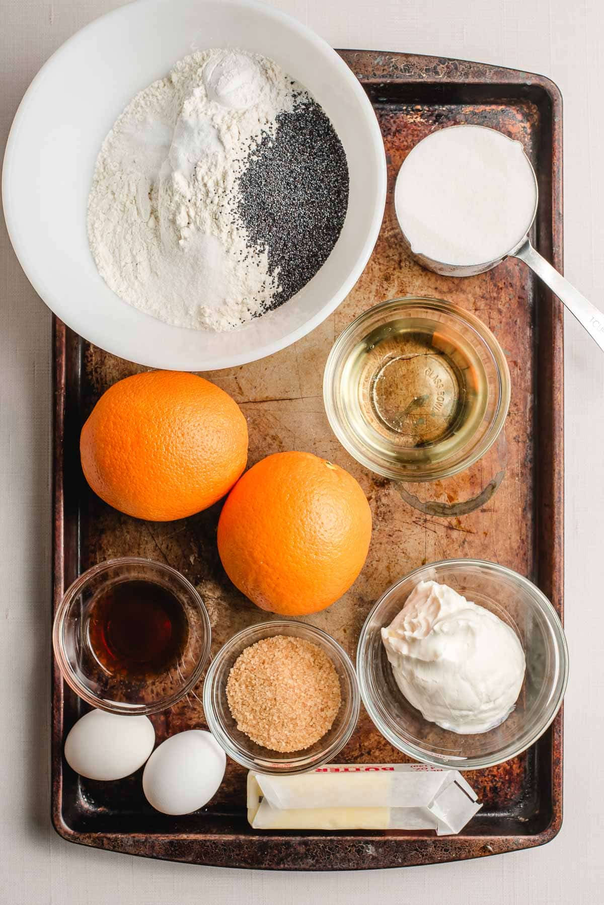 Ingredients for orange poppy seed muffins arranged on a sheet pan.