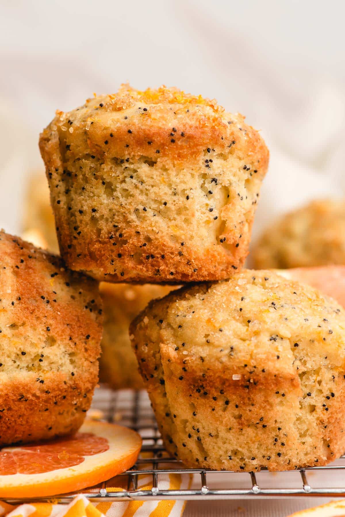 Orange muffins stacked on a cooling rack.
