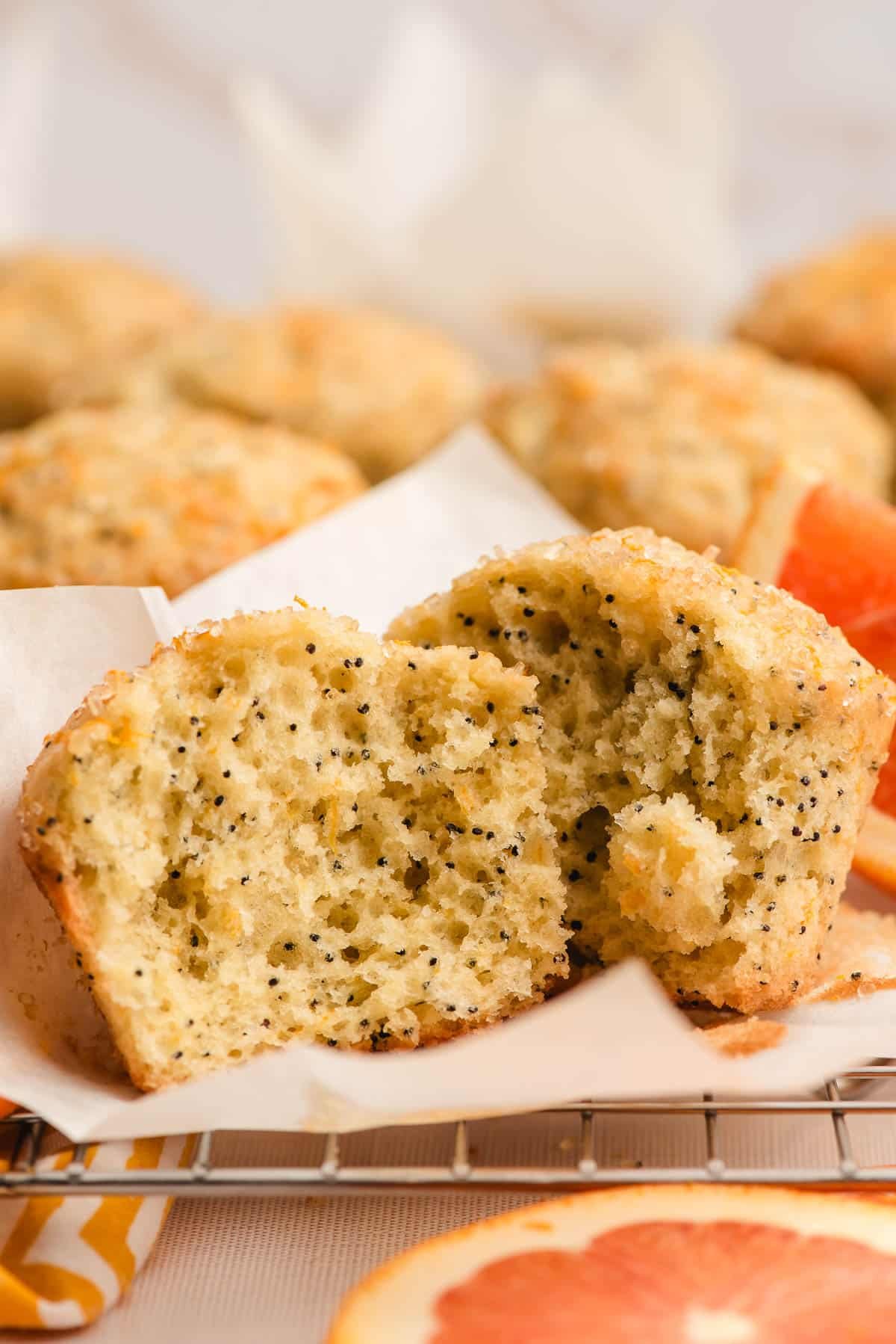 An orange and poppy seed muffin broken in half to show the fluffy interior.