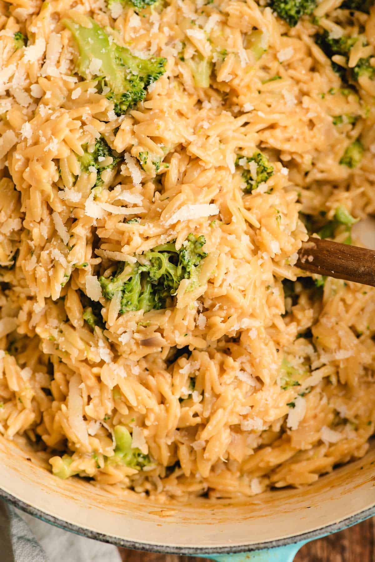 Cheesy Broccoli Orzo with a wooden spoon stirring it.