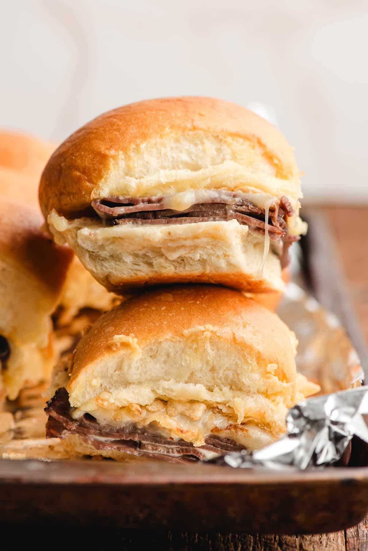 Stack of two roast beef sliders with melty cheese coming out the side.