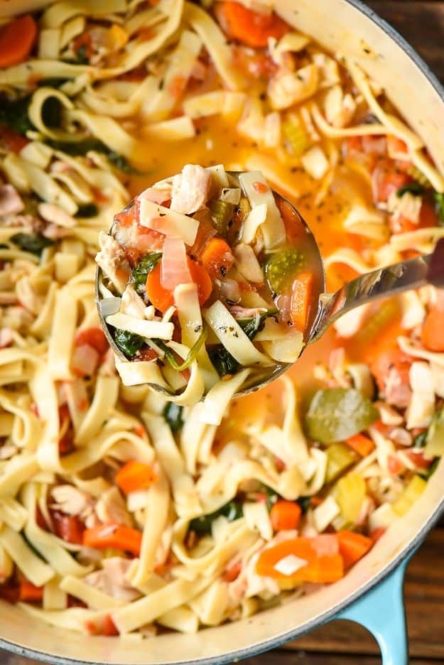 Easy chicken noodle soup in a Dutch oven with a ladle scooping some out.