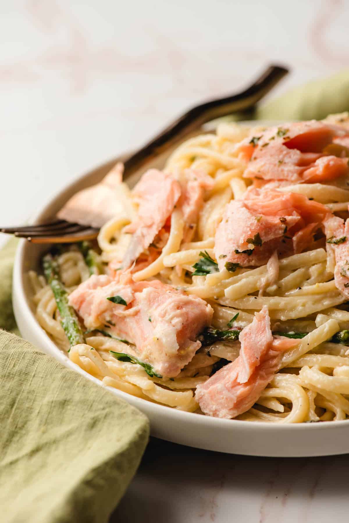 Creamy Salmon Linguine with asparagus on a white plate.