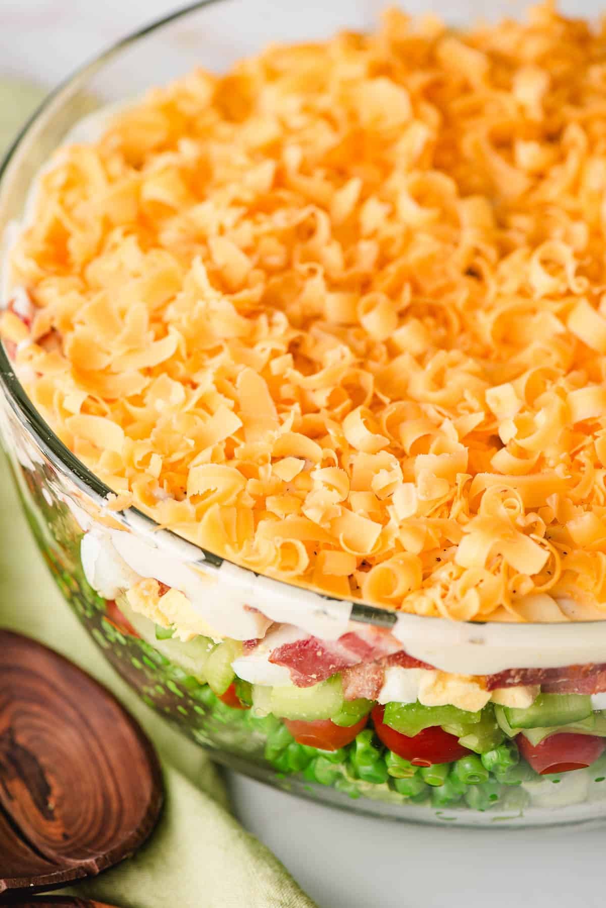 7 layer salad topped with shredded cheddar cheese.