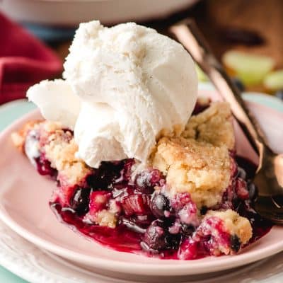 Slice of Blueberry Rhubarb Pie with a scoop of ice cream on top.