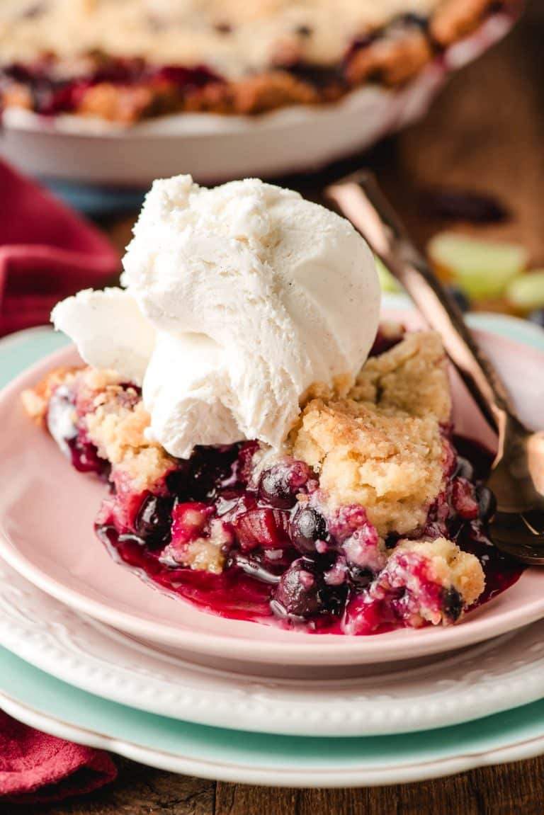 Slice of Blueberry Rhubarb Pie with a scoop of ice cream on top.