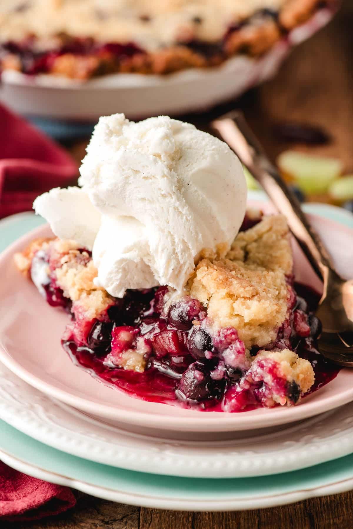 Slice of Blueberry Rhubarb Pie with a scoop of ice cream on top.