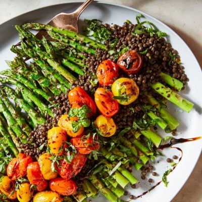 Grilled Asparagus with lentils and cherry tomatoes on a platter.