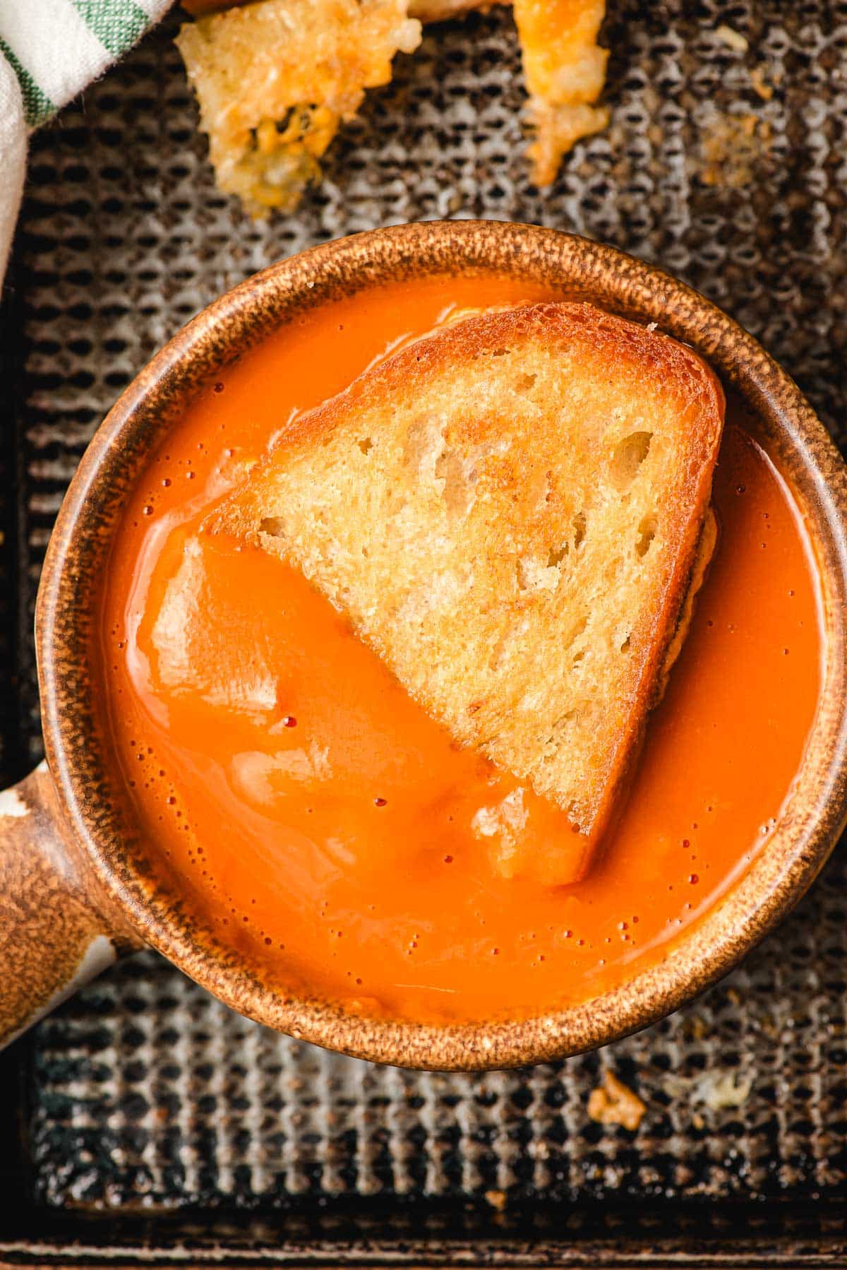 A grilled cheese sandwich dunked in a bowl of tomato soup.