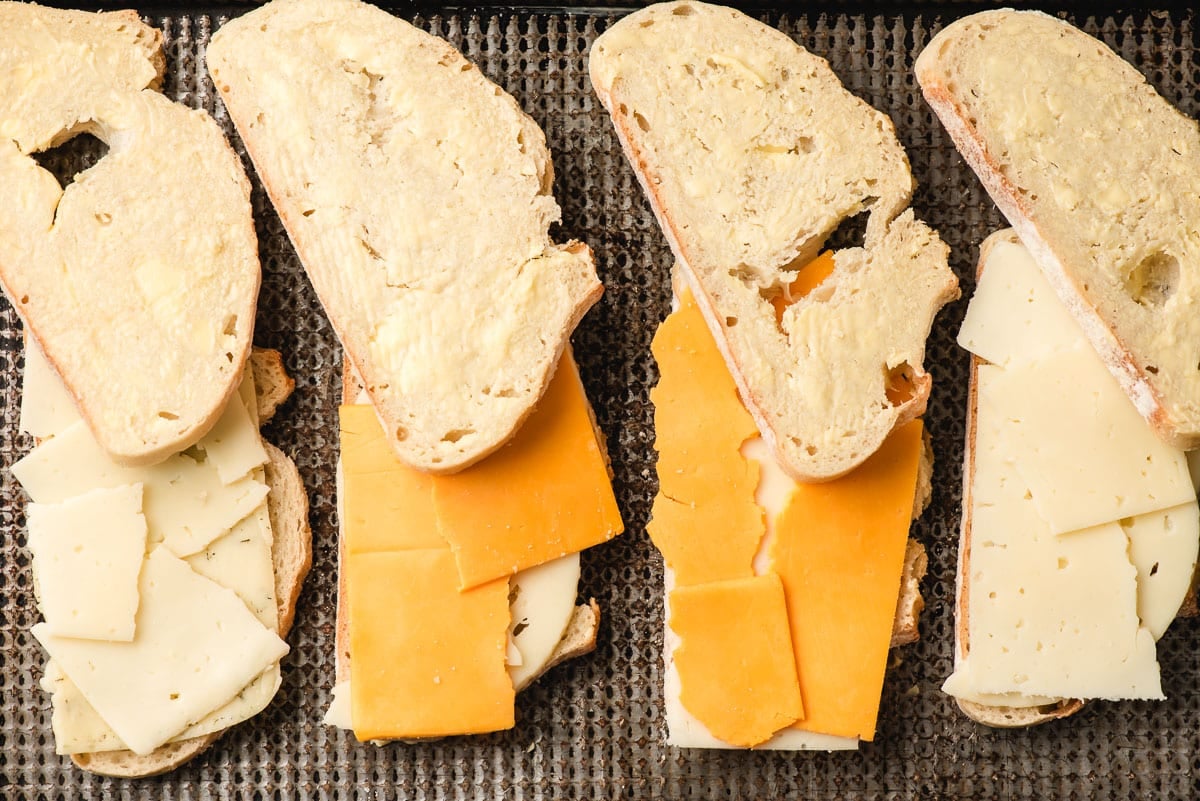 Grilled cheese sandwiches being assembled on a sheet pan.