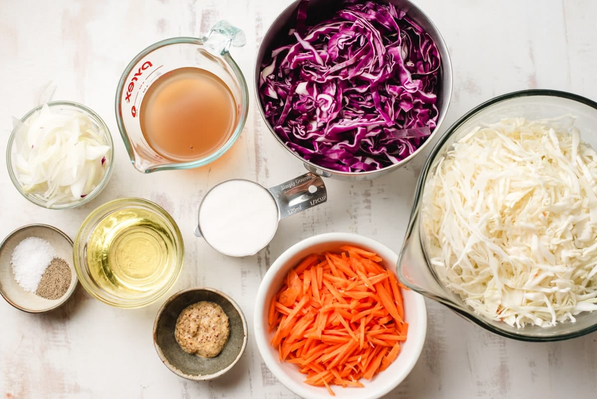 Shredded red and green cabbage, onion, carrots, apple cider vinegar, sugar, mustard, salt, and pepper.