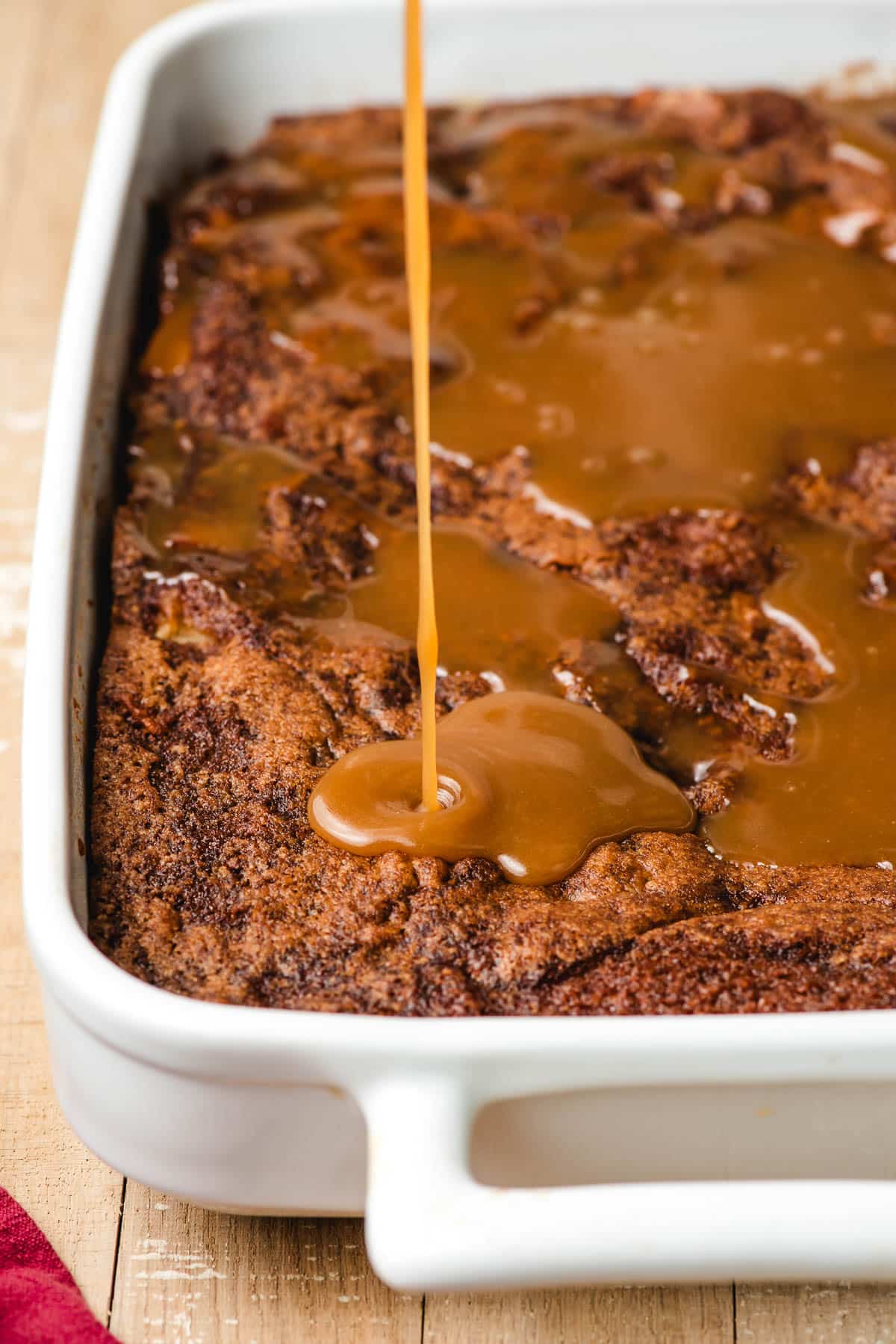 Caramel glaze being drizzle over an apple cake.