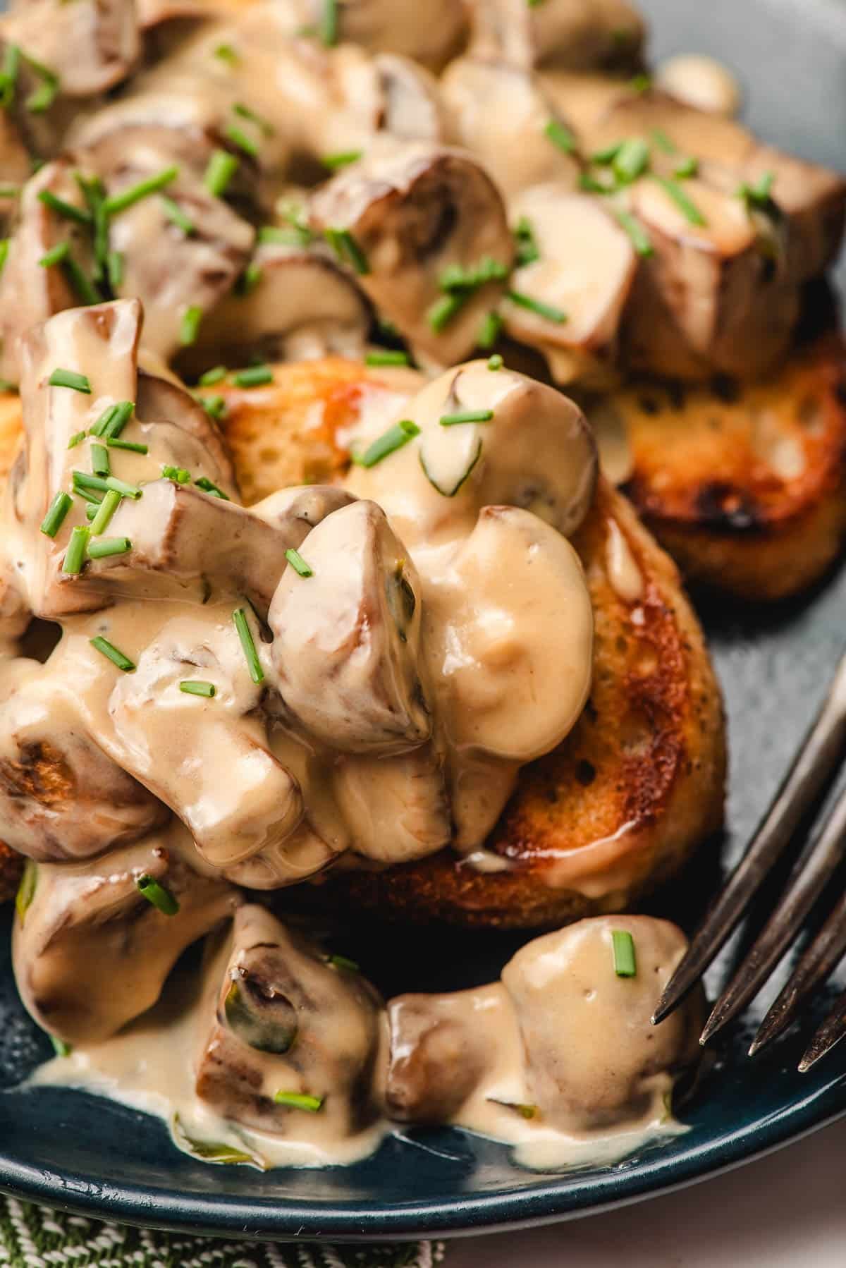 Creamy mushroom toast shown on a blue plate.