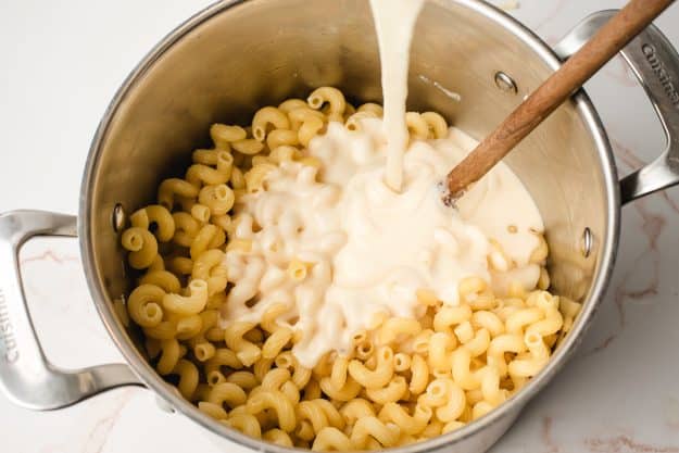 Cheese sauce being poured over cavatappi noodles.