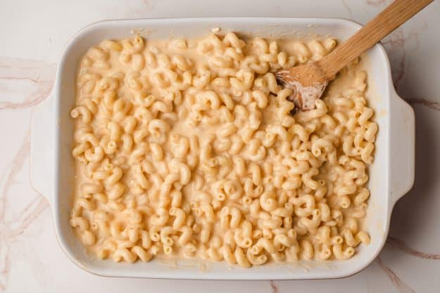 Cavatappi noodles stirred with creamy cheese sauce in a casserole dish.