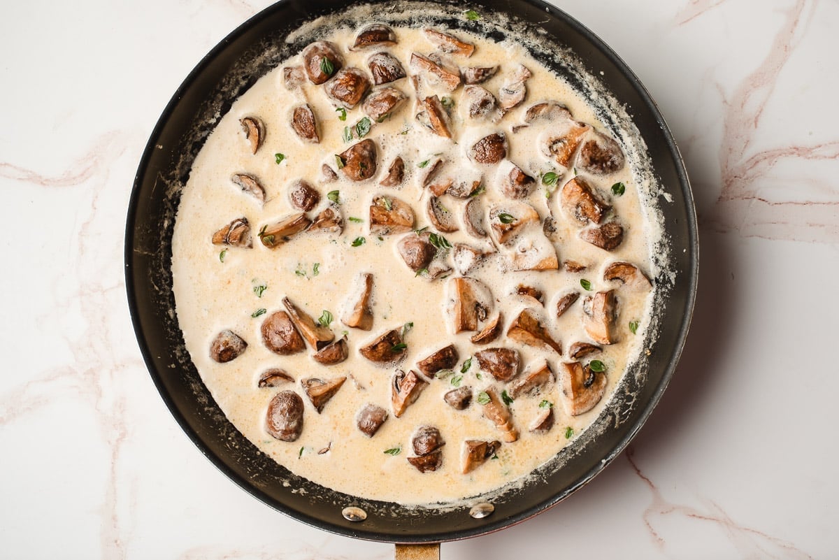 Cream and butter added to sauteed mushrooms and garlic in a pan.