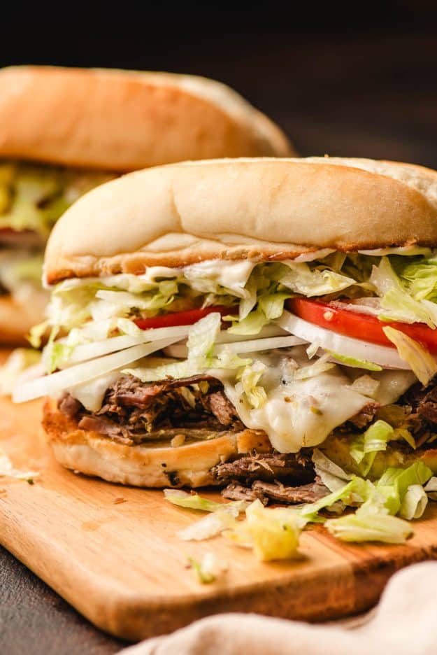 Shredded beef sandwich with cheese, lettuce, tomato, and onion.