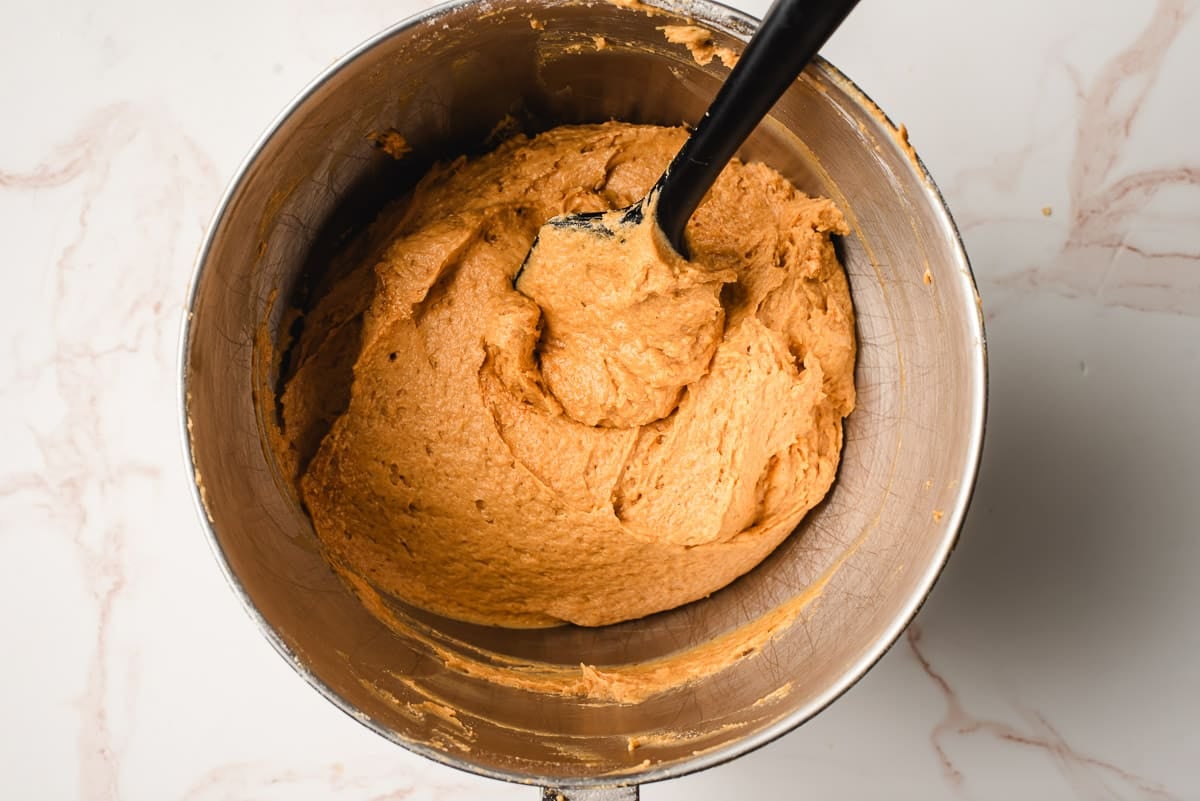 Soft pumpkin cookie dough in the bowl of an electric mixer.