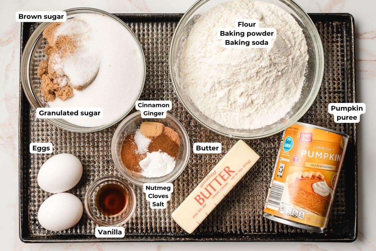 Brown and granulated sugars, eggs, vanilla, spices, flour, butter, and pumpkin puree in bowls.