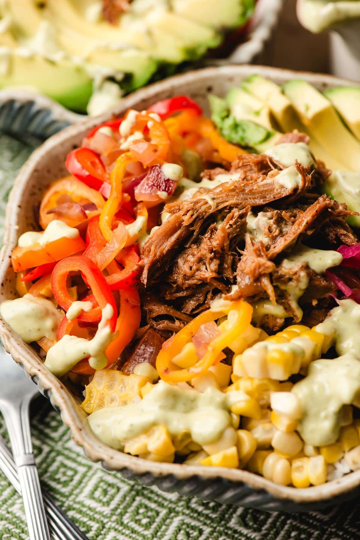 Pulled pork rice bowls with avocado dressing, corn, and sauteed peppers.
