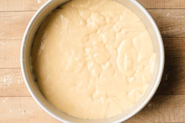 Yellow cake batter poured into a round cake pan.