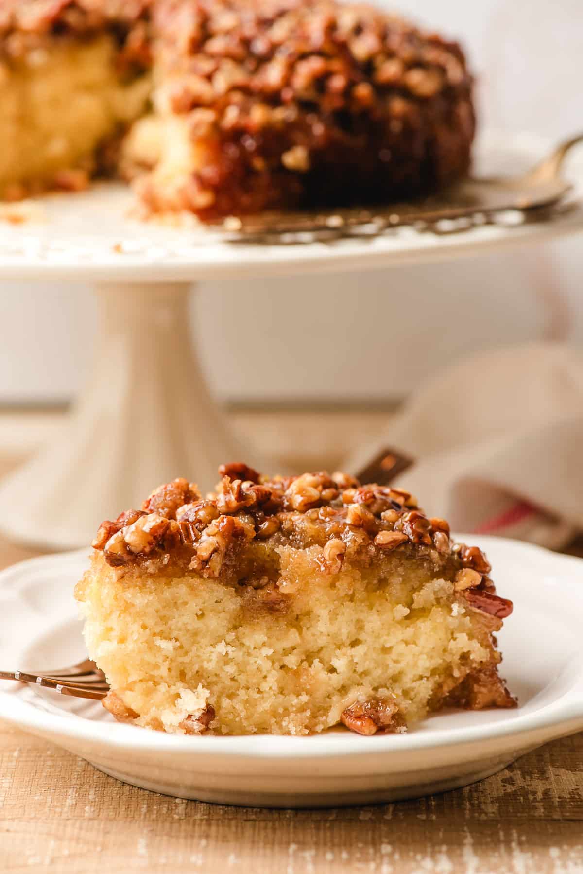 Slice of pecan upside down cake on a white plate.