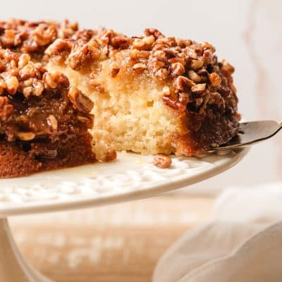 Slice of upside down pecan cake being taken off a serving platter.