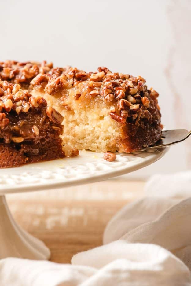 Slice of upside down pecan cake being taken off a serving platter.