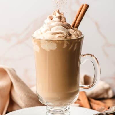 Cinnamon sprinkled over a latte piled high with whipped cream.