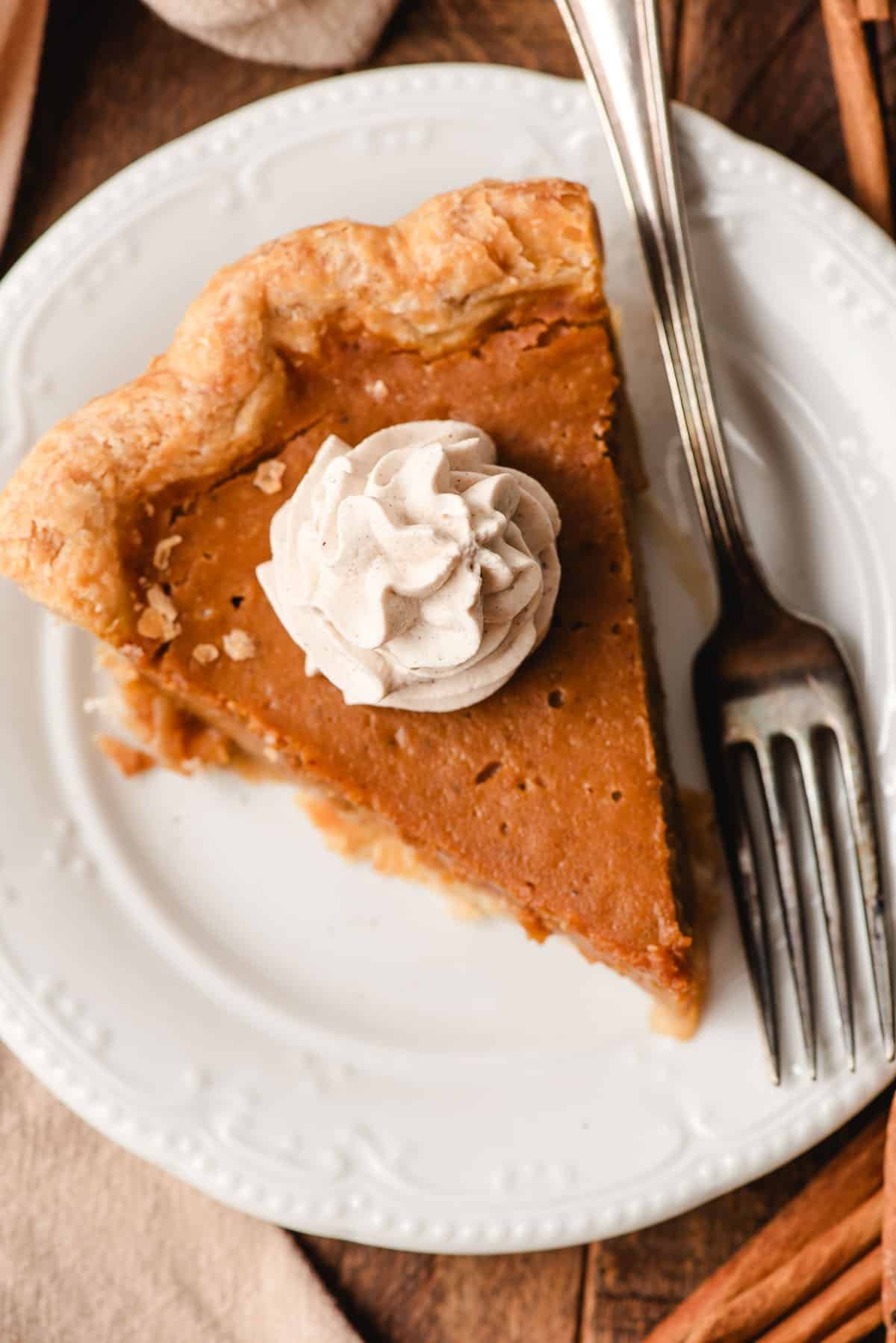 Dollop of cinnamon whipped cream on a slice of pumpkin pie.